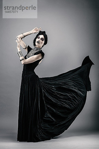 Junge Frau in schwarzem Kleid auf grauem Hintergrund