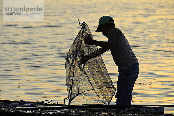 Silhouette eines Fischers bei Sonnenuntergang  Flores  Peten  Guatemala  Mittelamerika.