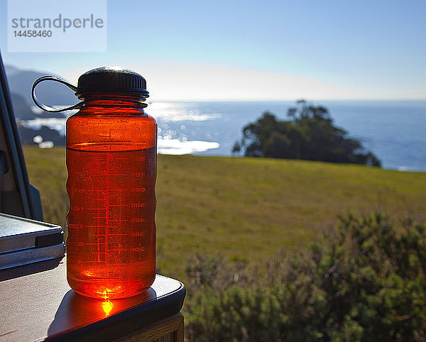 Rote Wasserflasche mit Ozean im Hintergrund