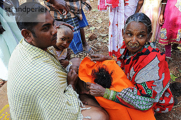 Stammesangehörige der Mali halten das Haar eines Kindes  dem der Kopf für Choula rasiert wurde  beim Shivraatri-Fest  Koraput  Odisha  Indien