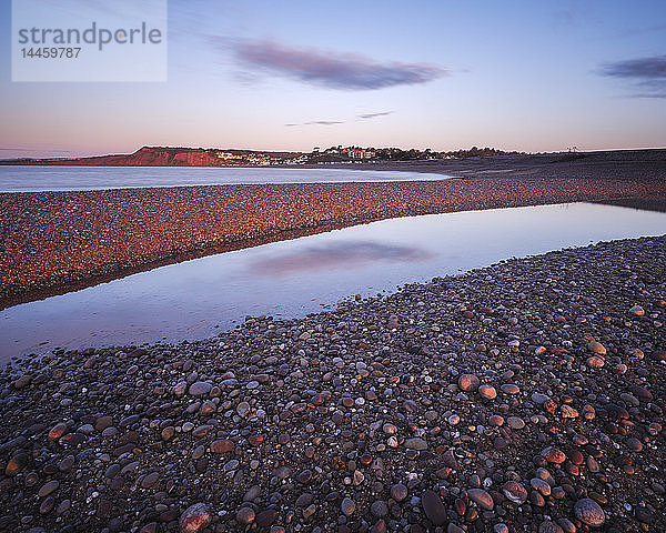 Das erste Sonnenlicht fällt auf Budliegh Salterton mit Kieselsteinen am geschwungenen Strand von Otter Mouth  Budleigh Salterton  Devon  England  Vereinigtes Königreich