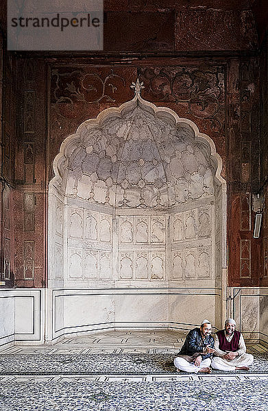 Männer sitzen am Bogen der Jama Masjid Moschee in Delhi  Indien