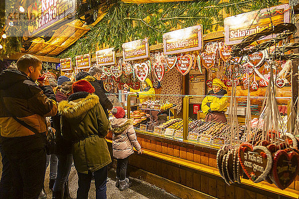 Menschen an einem nächtlichen Weihnachtsmarktstand auf dem Rathausplatz  Wien  Österreich