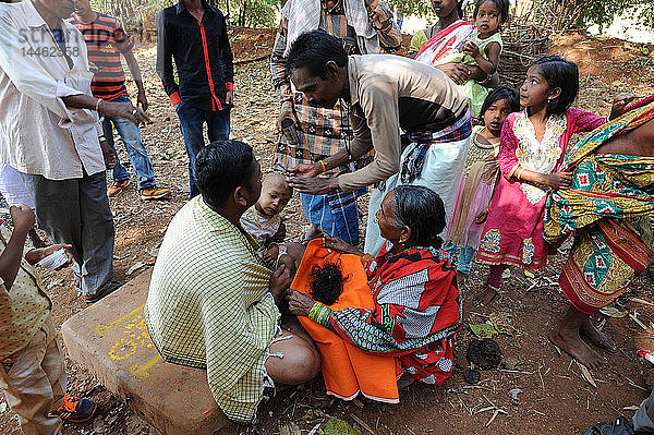 Stammesangehörige der Mali halten das Haar eines Kindes  dem der Tempelpundit beim Shivraatri-Fest den Kopf rasiert hat  Koraput  Odisha  Indien