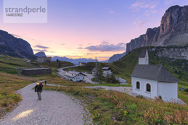 Wanderer geht auf einem Weg während des Sonnenaufgangs  Grödnerjoch  Grödnertal  Südtirol  Dolomiten  Italien