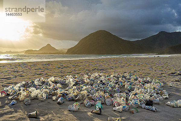 Haufen von Plastikmüll  der bei Sonnenuntergang am Selong Belanak Beach auf Lombok  Indonesien  Südostasien  in den Sand gekippt wird
