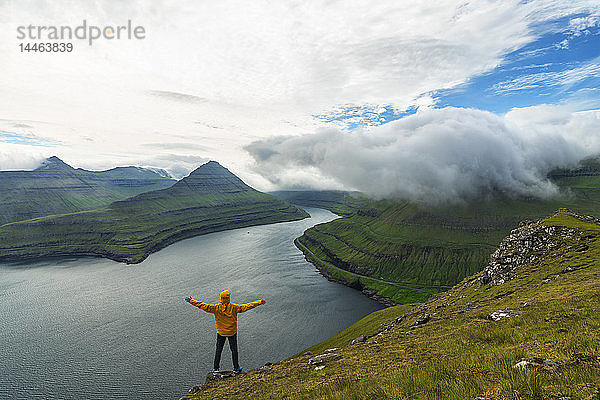 Ein Mann mit offenen Armen freut sich mit Blick auf die Fjorde  Funningur  Insel Eysturoy  Färöer Inseln  Dänemark