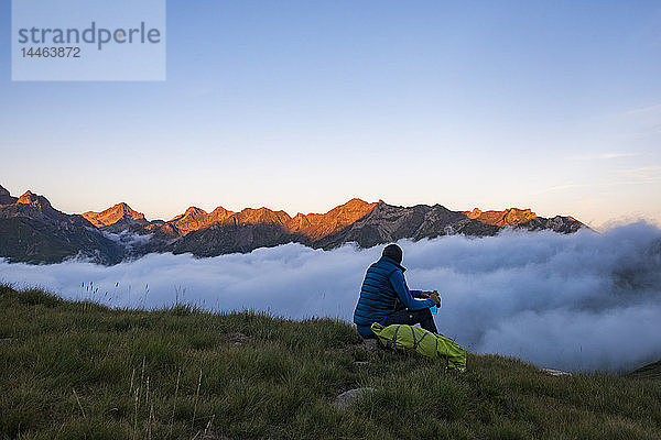 Ein Wanderer beobachtet den Sonnenuntergang in den Pyrenäen und eine Wolkeninversion in der Nähe der Schutzhütte Pombie entlang des GR10  Pyrenees Atlantiques  Frankreich