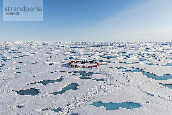 Menschen in Rot bilden einen Kreis um den Nordpol  Arktis