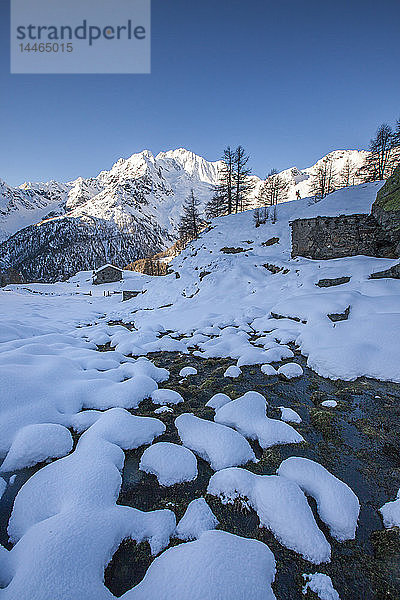 Schnee auf Felsen entlang des Baches mit dem Monte Vazzeda im Hintergrund  Alpe dell'Oro  Valmalenco  Valtellina  Lombardei  Italien