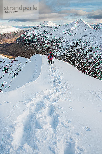 Eine Wanderin beim Abstieg vom Gipfel des Stob Dubh auf Buchaille Etive Beag an einem klaren Wintertag  Highlands  Schottland  Vereinigtes Königreich