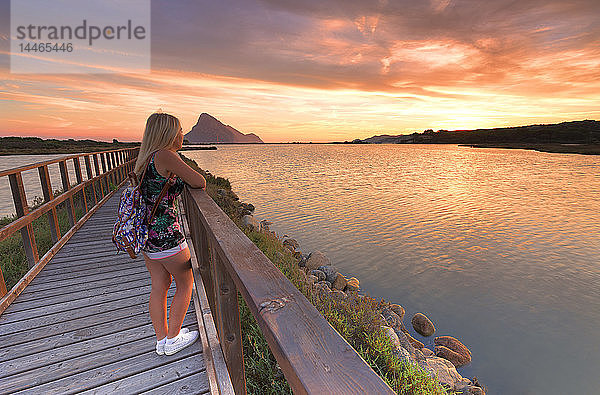 Ein Mädchen betrachtet den Sonnenaufgang von einem Spazierweg aus  Porto Taverna  Loiri Porto San Paolo  Provinz Olbia Tempio  Sardinien  Italien  Mittelmeer