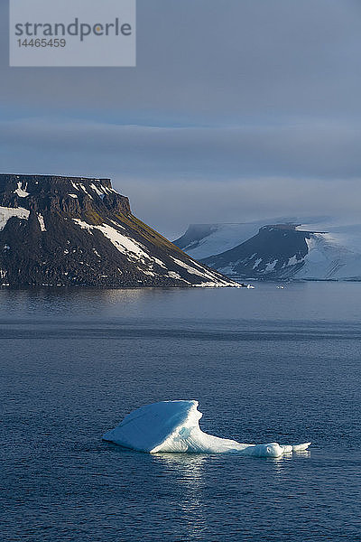 Eisberg  der vor einem flachen  mit Eis bedeckten Tafelberg schwimmt  Archipel Franz Josef Land  Gebiet Archangelsk  Arktis  Russland