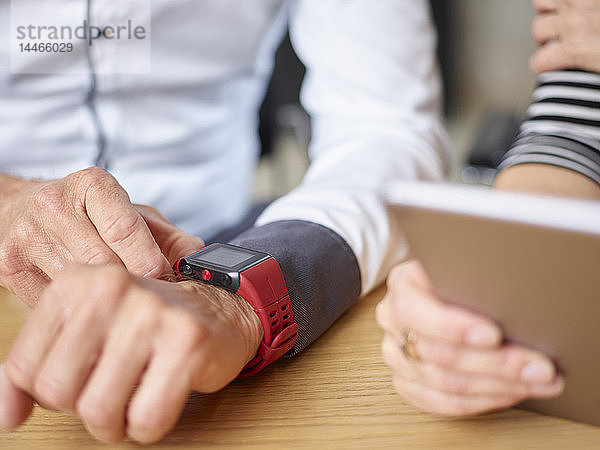 Nahaufnahme eines Geschäftsmannes und einer Geschäftsfrau mit Smartwatch und Tablet im Büro