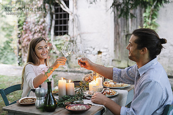 Paar beim romantischen Essen bei Kerzenschein neben einer Hütte und klirrenden Weingläsern