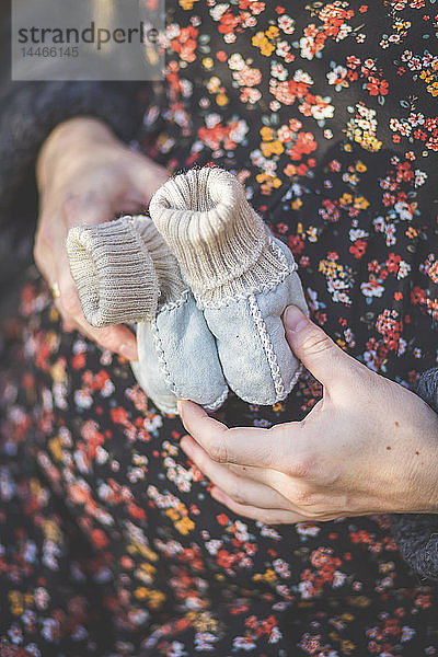 Nahaufnahme einer schwangeren Frau mit Babyschuhen