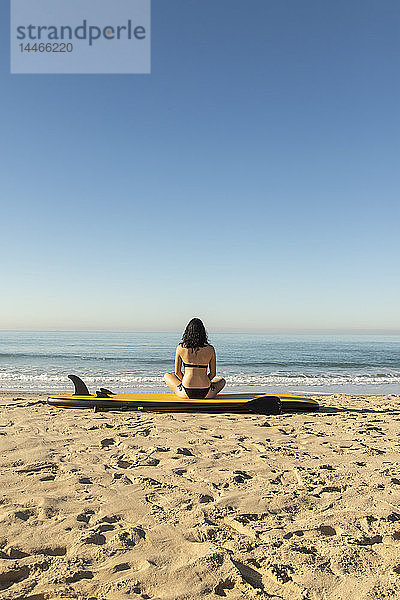 Spanien  Andalusien  Tarifa  Frau sitzt auf einem Stehpaddelbrett am Strand