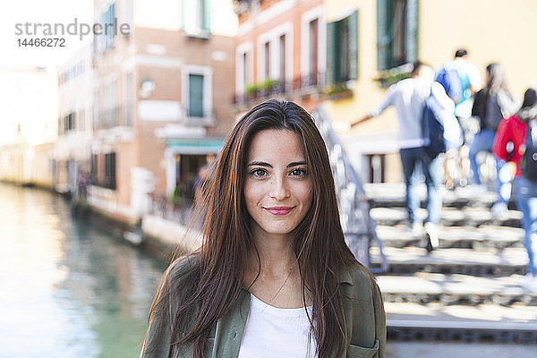 Italien  Venedig  Porträt einer lächelnden jungen Frau in der Stadt mit Kanal im Hintergrund