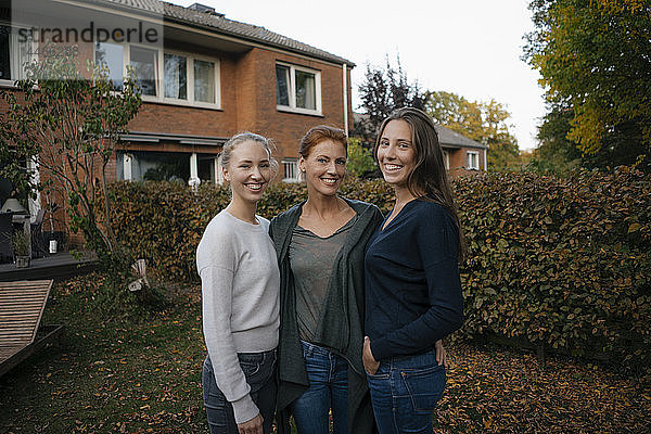 Porträt einer glücklichen Mutter mit zwei Teenager-Mädchen im Herbst im Garten