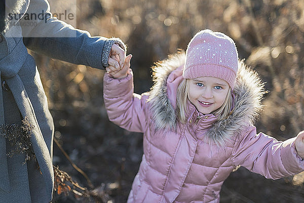 Porträt eines kleinen Mädchens Hand in Hand mit seiner Mutter auf einer herbstlichen Wiese zur goldenen Stunde