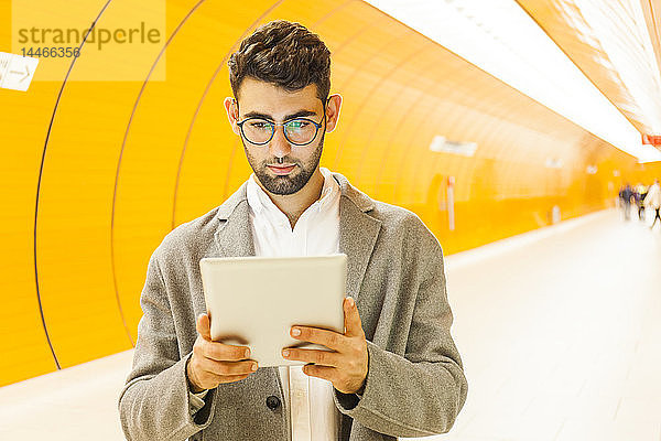Deutschland  München  Porträt eines jungen Geschäftsmannes mit digitalem Tablet in der U-Bahn-Station