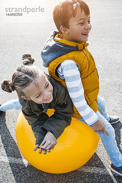 Kleine Jungen und Mädchen haben Spaß am Gymnastikball