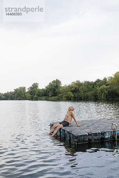 Älterer Mann sitzt auf einem Floß in einem See