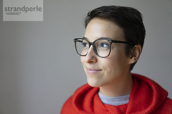 Porträt einer lächelnden jungen Frau mit kurzen Haaren  die eine Brille trägt