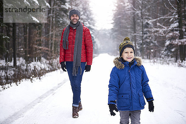 Porträt eines glücklichen kleinen Jungen  der zusammen mit seinem Vater im Winterwald spazieren geht