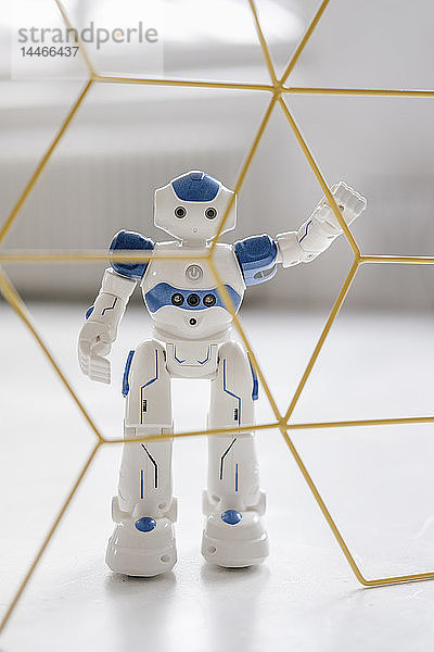 Miniatur-Roboter-Figur  die hinter einer Struktur steht