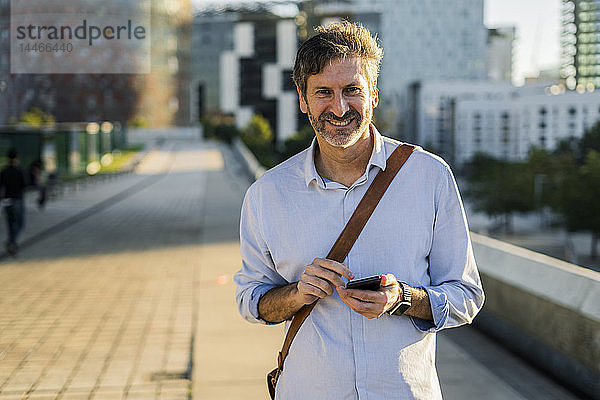 Porträt eines lächelnden reifen Mannes mit Handy in der Stadt
