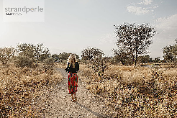 Afrika  Namibia  blonde Frau auf dem Weg im Grasland