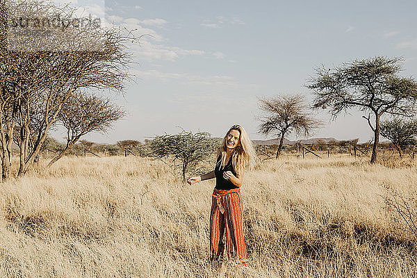 Afrika  Namibia  blonde lächelnde Frau steht im Grasland