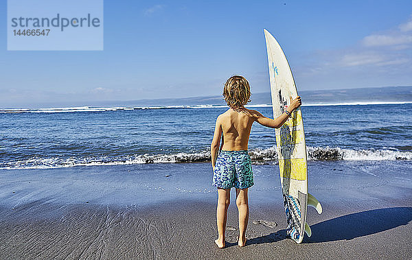 Chile  Pichilemu  Junge mit Surfbrett am Meer stehend