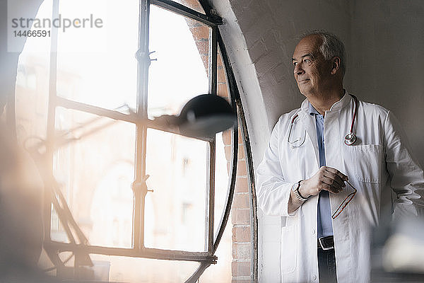 Leitender Arzt schaut in der medizinischen Praxis aus dem Fenster