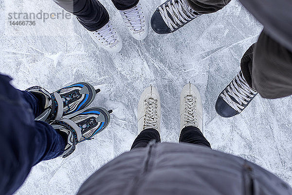 Familie mit zwei Kindern auf der Eisbahn stehend  Nahaufnahme der Schuhe