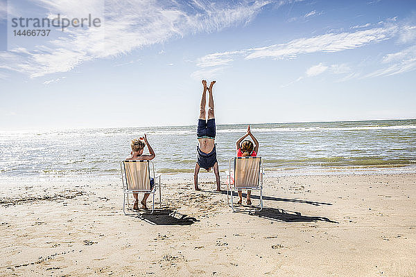 Niederlande  Zandvoort  Kinder klatschen für Vater beim Handstand am Strand in die Hände