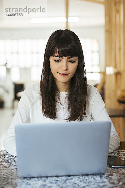 Porträt einer jungen Frau mit Laptop auf Tisch