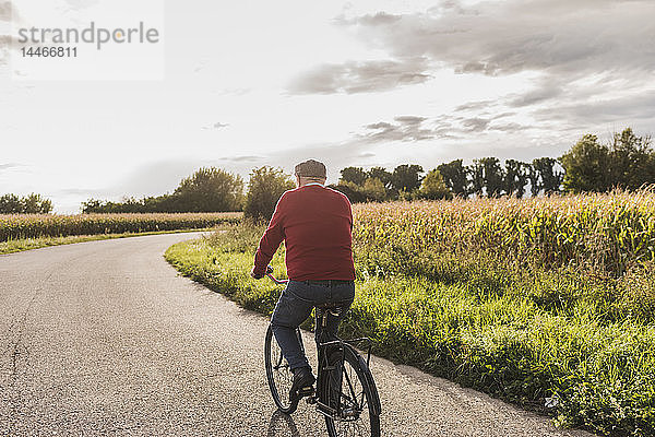 Älterer Mann fährt Fahrrad auf dem Feldweg