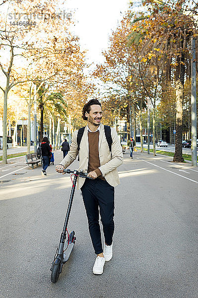 Lächelnder Mann mit Rucksack E-Scooter in der Stadt