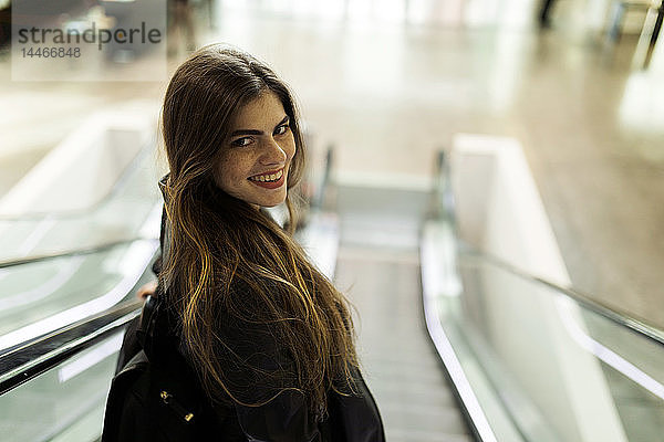 Porträt einer lächelnden jungen Frau auf der Rolltreppe