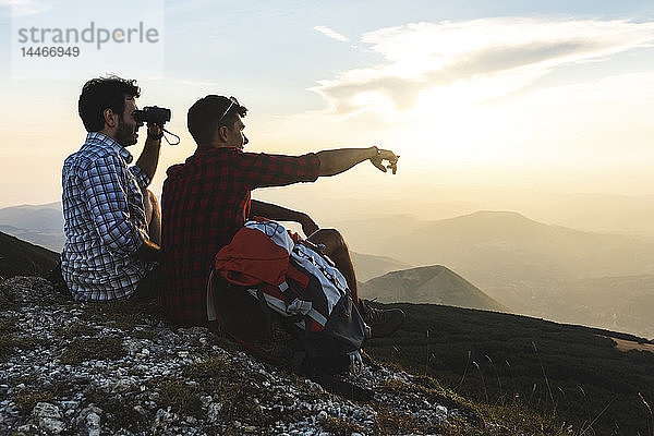 Italien  Monte Nerone  zwei Wanderer auf dem Gipfel eines Berges  die bei Sonnenuntergang die Aussicht geniessen