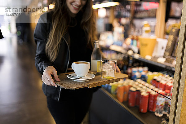 Nahaufnahme einer Frau mit Tablett mit Kaffee und Erfrischungsgetränk in einem Selbstbedienungscafé