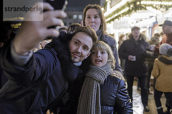 Familie mit Smartphone auf dem Weihnachtsmarkt