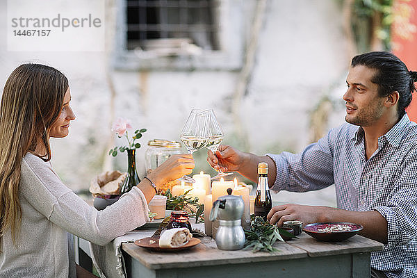 Paar beim romantischen Essen bei Kerzenlicht und klirrenden Weingläsern