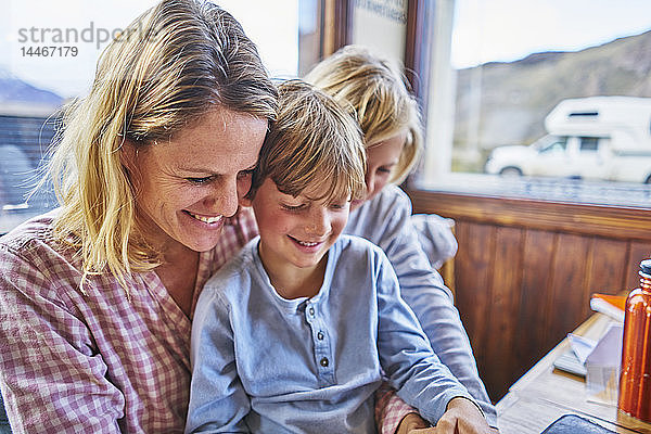 Glückliche Mutter mit zwei Söhnen  die in einem Café am Tisch sitzen