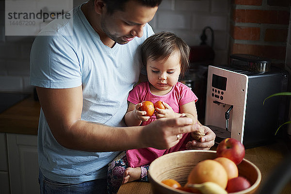 Vater und kleines Mädchen essen zu Hause Obst in der Küche