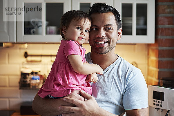 Lächelnder Vater hält Mädchen zu Hause in der Küche