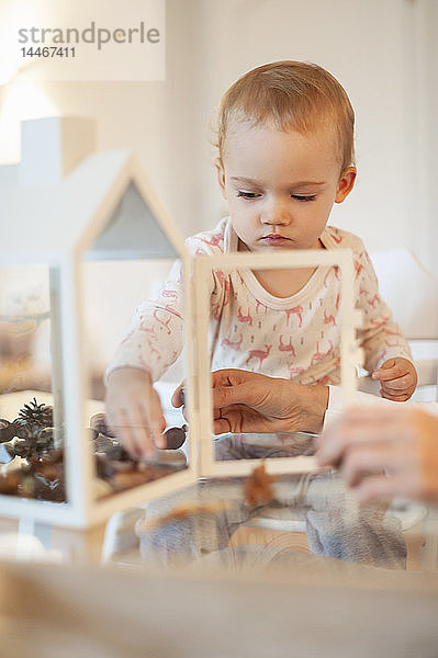 Mutter und kleine Tochter basteln zu Hause an herbstlich dekorativem Haus