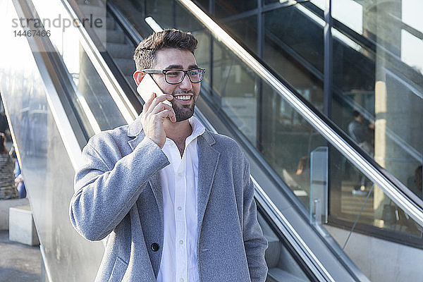 Porträt eines lächelnden jungen Geschäftsmannes am Telefon